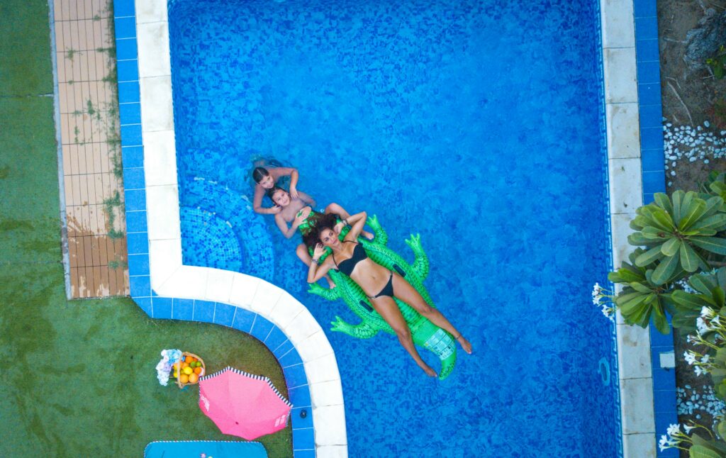pexels-photo-1506996-1506996 Aerial shot of three people having fun in a pool in Dubai with floaties and refreshments.